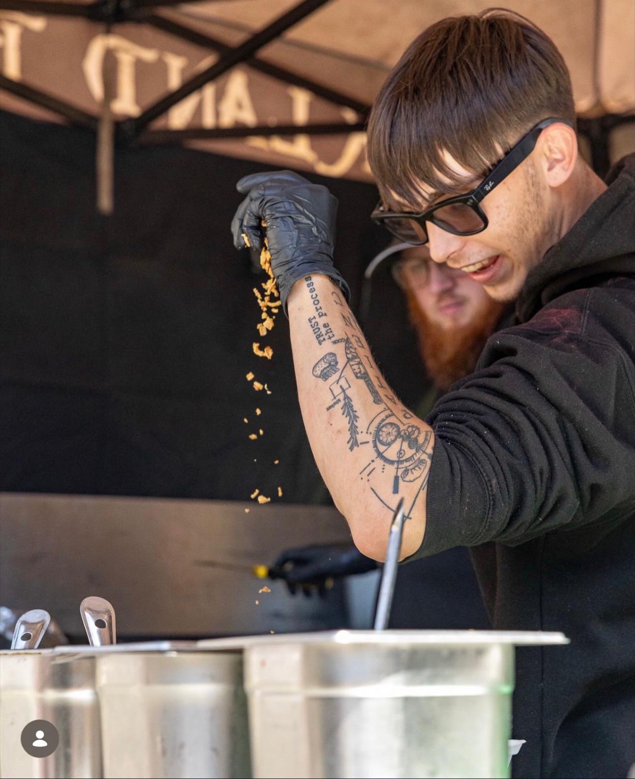 Chef sprinkling crispy onions under the Buckland Burgers gazebo